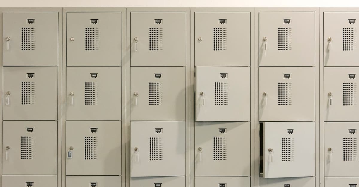 A row of grey metal lockers indoors with some doors ajar.