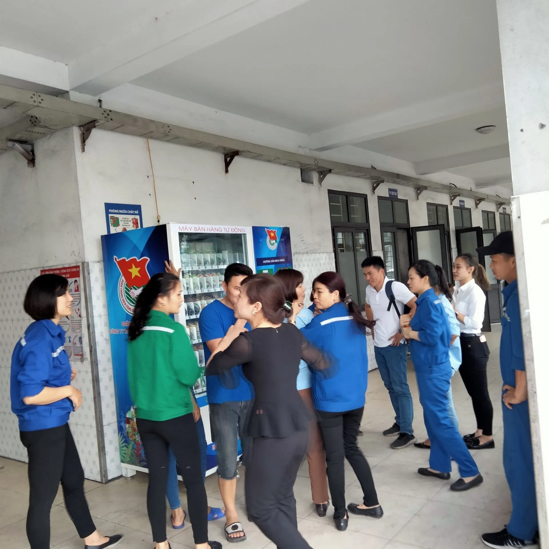 Máy bán hàng tự động tại hành lang tòa nhà, nhóm người bên cạnh