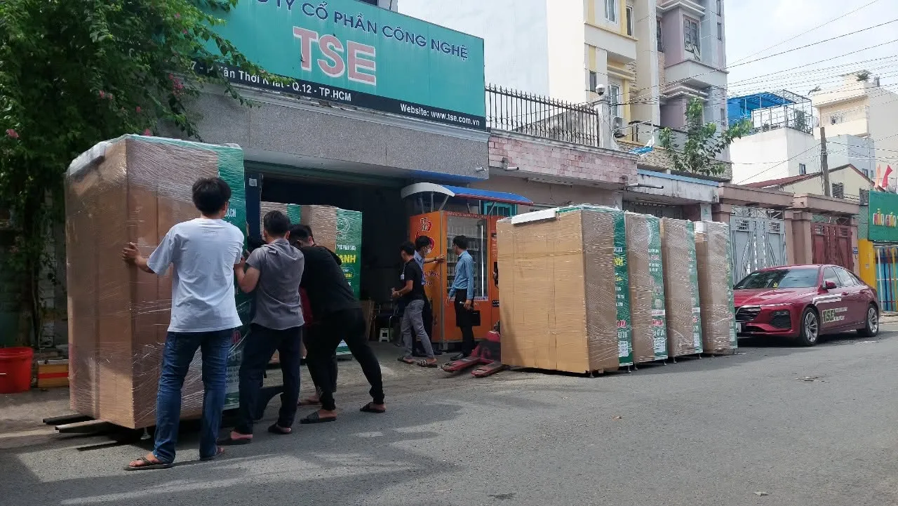 Nhân viên TSE đẩy máy bán hàng tự động đã đóng kiện ra vỉa hè trước trụ sở công ty để giao đi