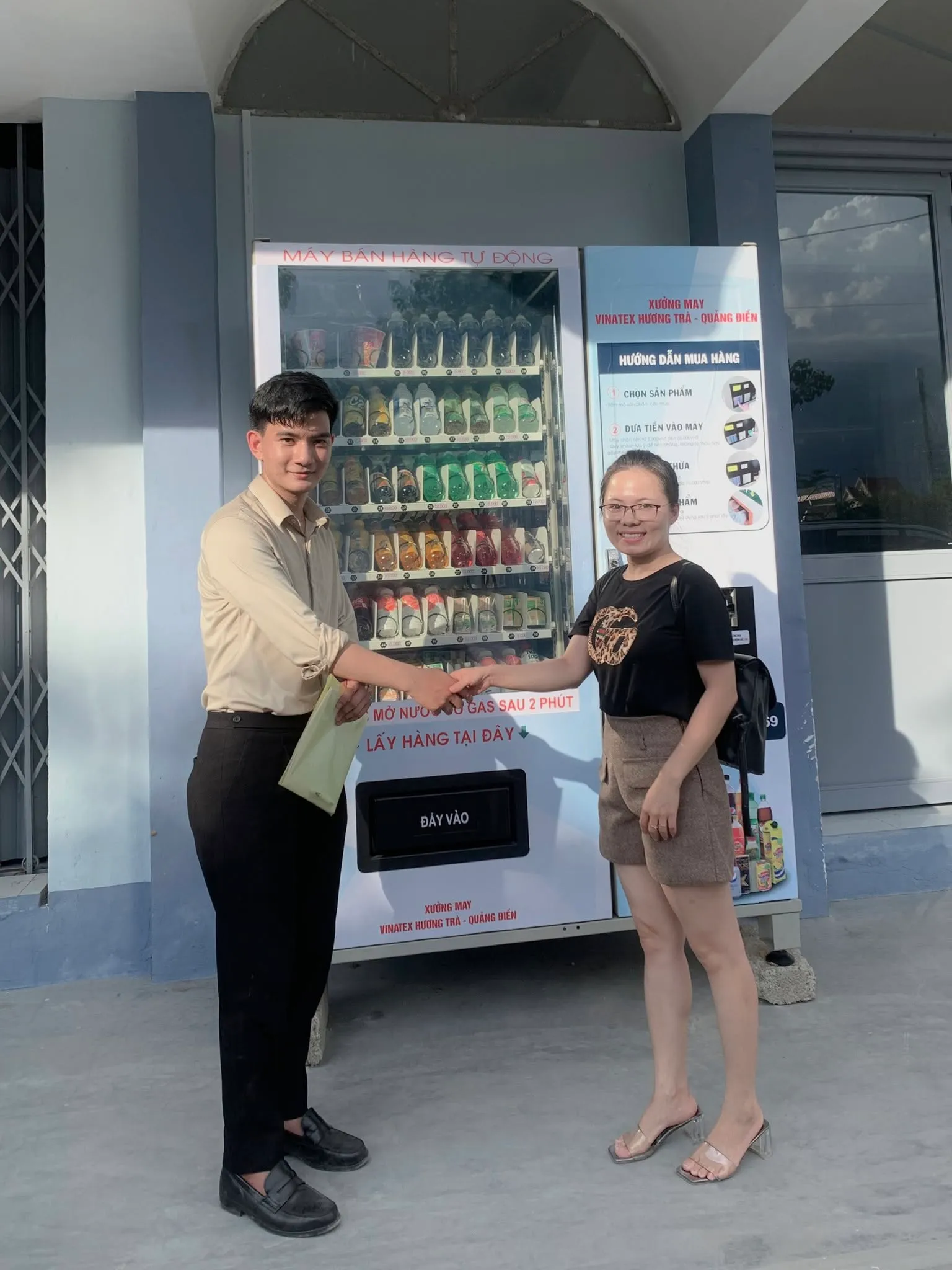 Đại diện TSE và khách hàng bắt tay trước máy bán hàng tự động vừa lắp đặt tại xưởng may Vinatex