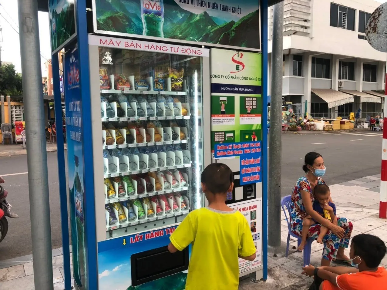 Máy bán nước tự động đặt trước cửa hàng tại khu dân cư, người dân đứng mua