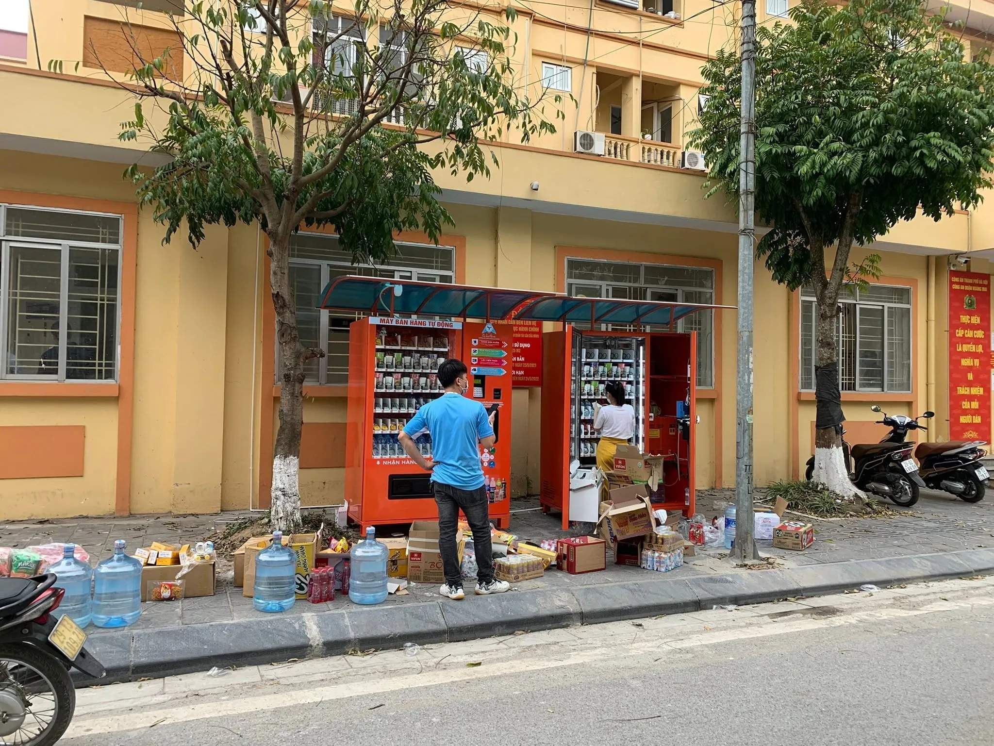 Người vận hành nạp thêm nước ngọt lon vào máy bán hàng tự động đang mở cửa trên vỉa hè
