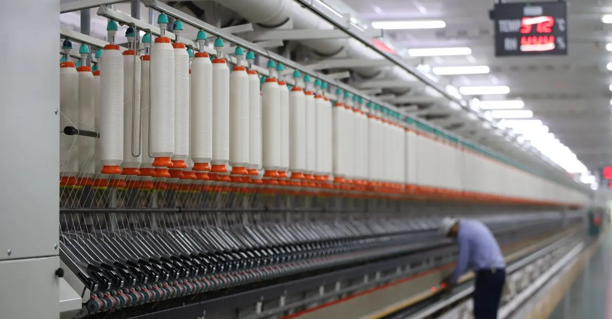 A factory worker records details in a textile manufacturing plant, showcasing industry and precision.